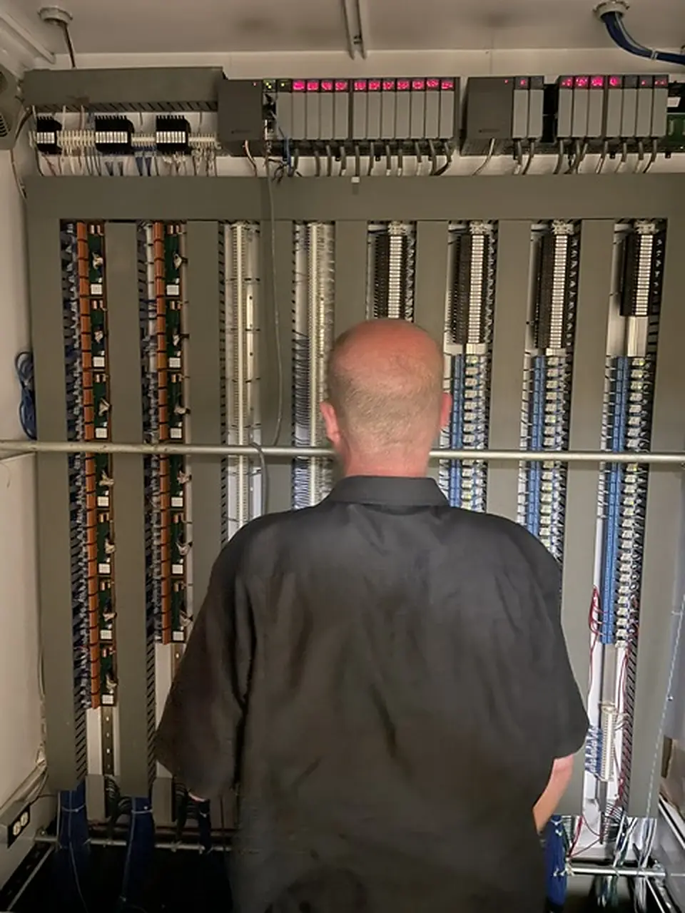 AE technician working at a wall of PLC terminations