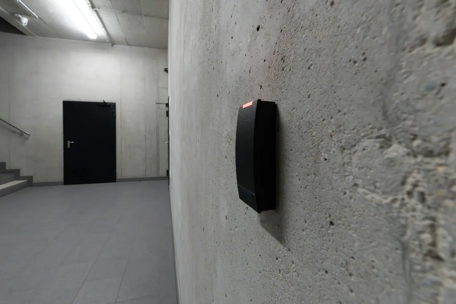 Card reader mounted on a concrete wall beside a secure door